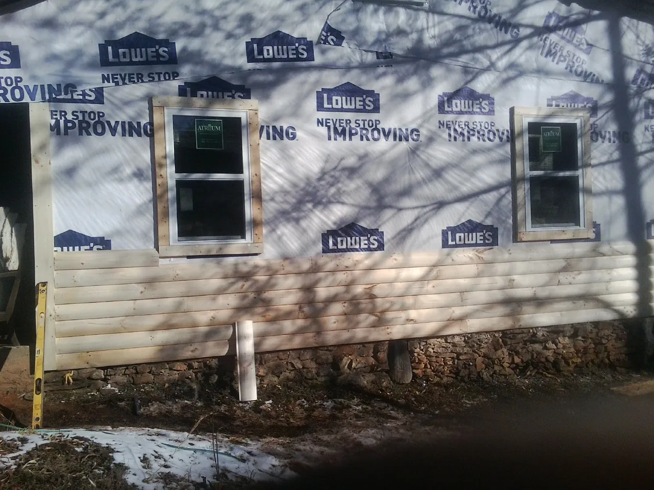 House wrap and new log siding going up on an exterior wall in Reevesville