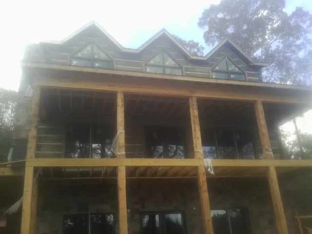 Dormers and porch framing on a large log home under construction — Roof Coating work by our crew in Reevesville