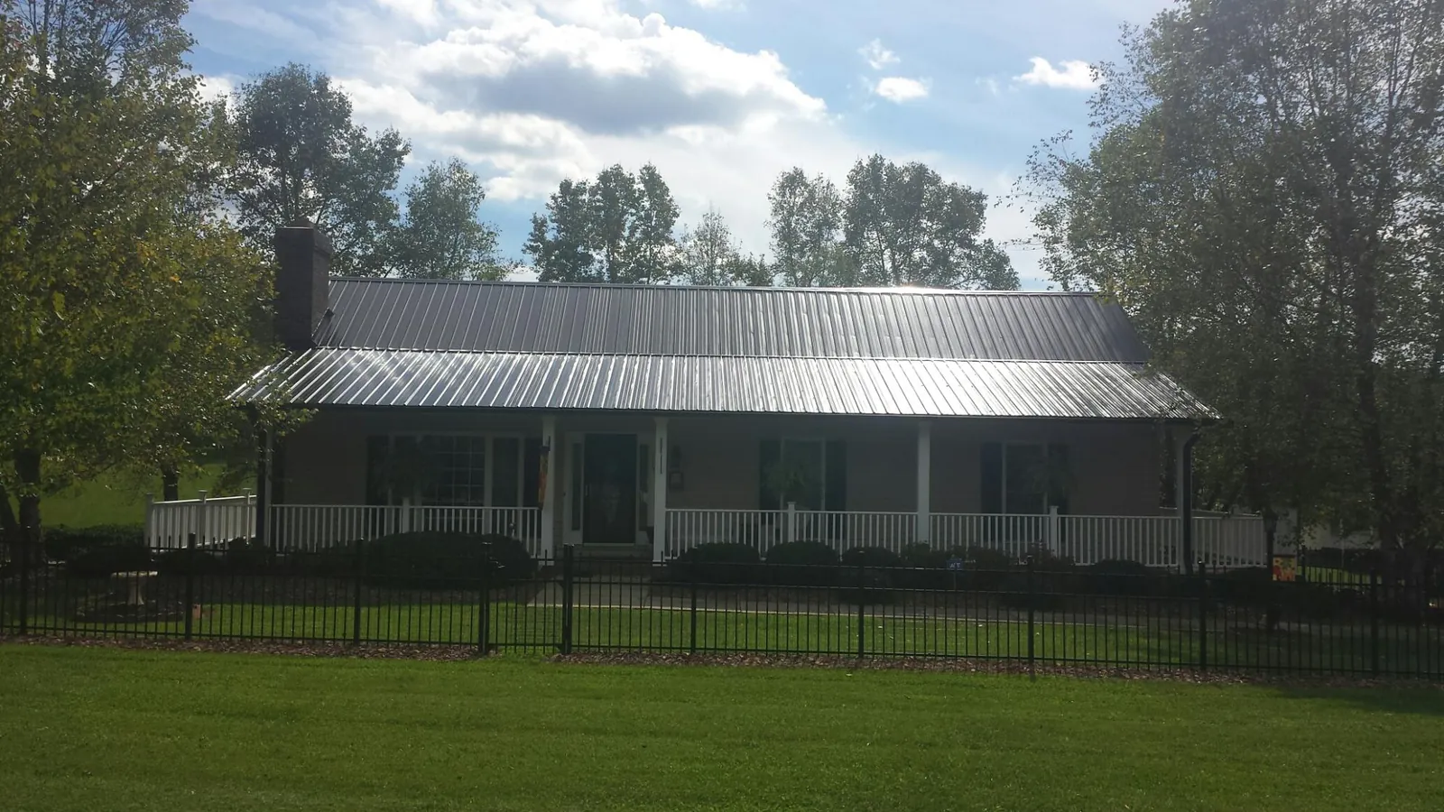 Gray metal roof on a brick ranch with a full width front porch — Gutter Guard Installation work by our crew in Reevesville