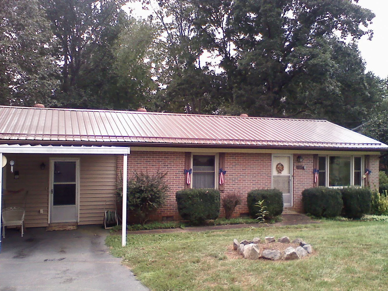 Bronze metal roof and carport on a brick ranch home — Roof Repair work by our crew in Reevesville