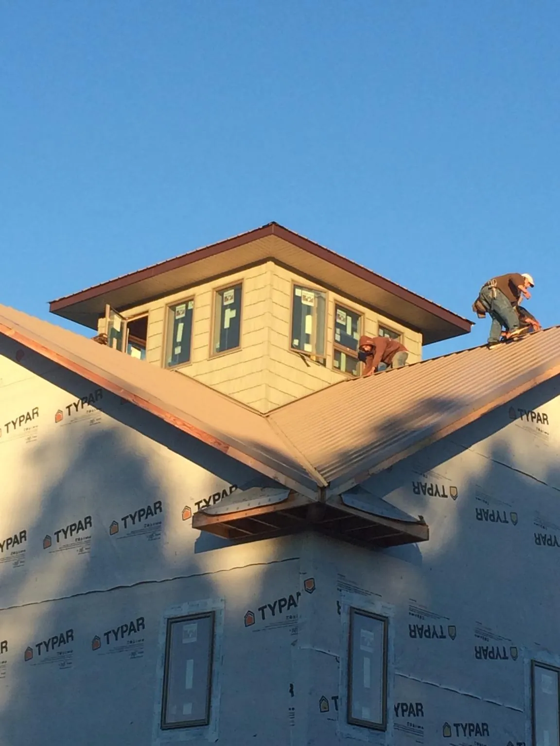 Roofers working around a rooftop cupola on a new metal roof at sunset — Roof Waterproofing in Reevesville by Roofing Brothers